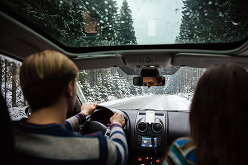 A couple in a car driving on a snow covered road