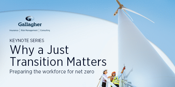 Two workers standing next to a wind turbine.